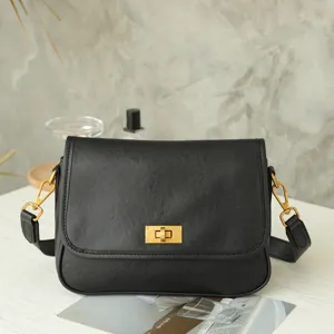 Detailed view of black leather vintage crossbody shoulder bag with golden metal hardware lock.