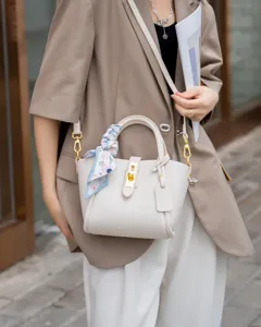 Close-up detail of premium genuine leather bucket handbag featuring metal lock design.