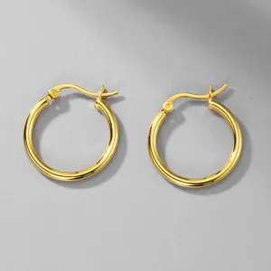 Detail view of golden 316L stainless steel minimalist hoop earrings on a gray background