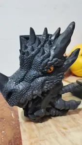 Detail der Schuppentextur und des orangefarbenen Auges einer schwarzen Drachen-Buchstütze.