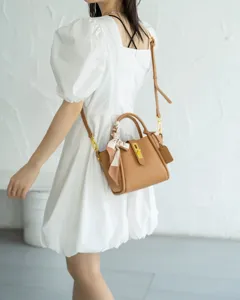 Elegant genuine leather crossbody tote bag with top handle and chic twist lock design.