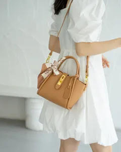 Detail shot of brown leather handbag with silk scarf, elegant crossbody bag worn by model.