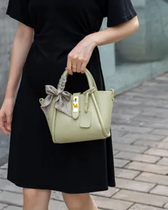 Light green leather bucket bag detail showing premium cowhide texture and chic ribbon.
