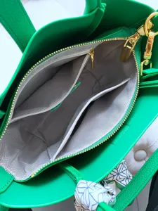 Green leather handbag interior detail, structured tote with gold hardware and compartments.