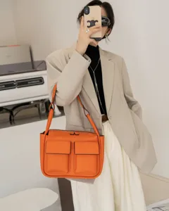 Orange leather shoulder tote bag with front pockets, stylish large capacity daily handbag for women.
