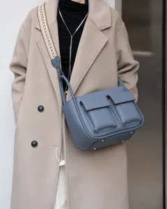 Detail shot of genuine leather crossbody bag with double front pockets and wide strap.