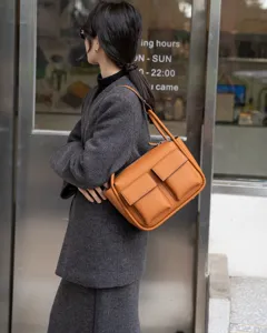Close-up detail of the stylish orange Togo leather shoulder bag featuring practical front pockets.