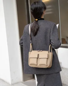 Detail shot of the genuine leather crossbody bag worn by model, showing front pockets and strap.