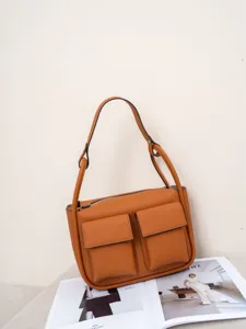 Brown genuine leather shoulder bag with front pockets and top zip closure for women.