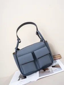 Detail shot of blue leather shoulder bag with front pockets and elegant top handle.