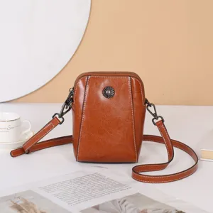 Vue détaillée du sac bandoulière marron en cuir huilé avec fermoir fleur métal et sangle.