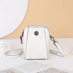 Vue détaillée du sac bandoulière en cuir blanc avec ornement de fleur en métal élégant.