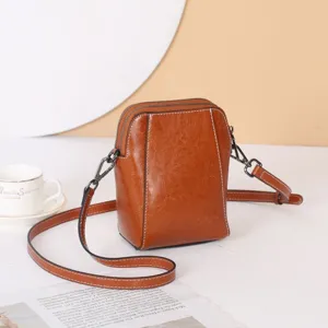 Vue détaillée du sac bandoulière en cuir ciré marron avec double fermeture éclair et sangle.