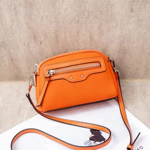 Orange leather crossbody bag detail, chic mini shoulder bag with zipper and studs for women.