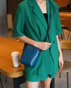 Vue détaillée du sac bandoulière en cuir bleu pour téléphone, avec coutures et rivet floral.