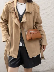 Detailed shot of a stylish brown leather crossbody bag worn by a model in casual outfit.