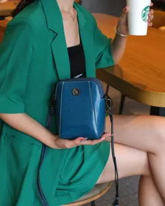 Vue détaillée de l'élégant sac bandoulière en cuir ciré bleu dans un café chaleureux.