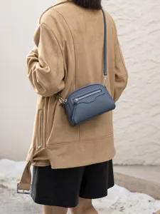 Detailed view of the elegant blue leather crossbody bag showcasing metal studs and zipper.
