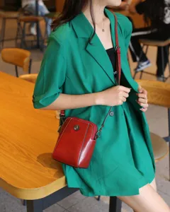 Vue détaillée d'un sac bandoulière rouge en cuir ciré pour téléphone avec décoration florale.