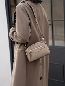 Detailed view of genuine leather crossbody bag with front zipper pocket and stylish metal accents.