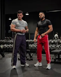 Men's short sleeve fitness compression shirt and athletic training pants set for gym workouts.