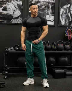 Close-up gym detail of men's compression athletic t-shirt and track pants, breathable fit.
