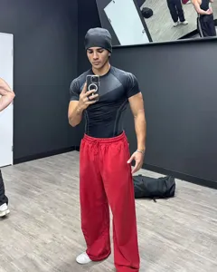 Men's gym fit detail showcasing tight black training compression shirt and red sweatpants.