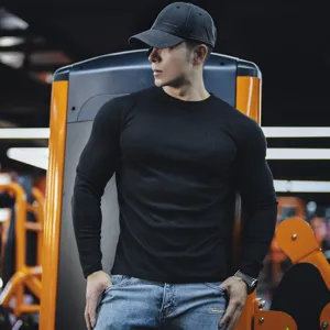 Close-up detail view of mens black ribbed long sleeve crewneck t-shirt in gym setting.
