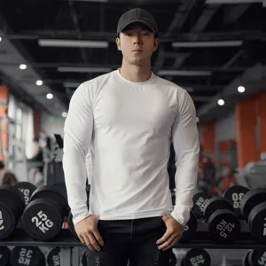 Detailed view of the men's solid white long-sleeve fitness T-shirt worn by a model in a gym setting.