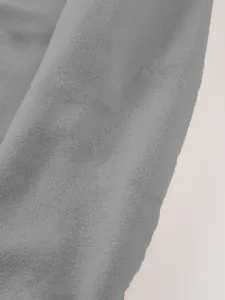 Gedetailleerd overzicht van zachte grijze fleecestof met warme textuur en knus materiaal.