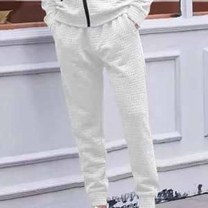Detail shot of men's white textured jacquard casual trousers, featuring elastic drawstring cuffs.