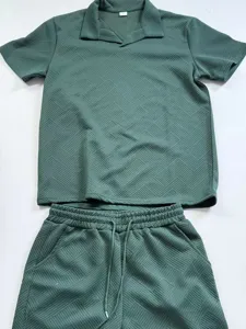 Detailansicht des dunkelgruenen geometrisch strukturierten Kurzarm-Poloshirts und Shorts.