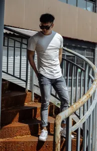 Men's athletic short sleeve t-shirt styled with ripped jeans in outdoor model detail shot.