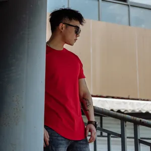 Detail view of a solid red short sleeve fitness t-shirt worn by a model outdoors.