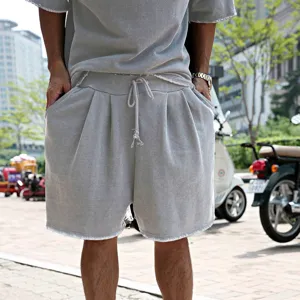Close-up detail of men's grey washed casual t-shirt and loose shorts set with raw hem.