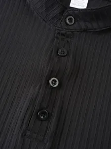Close-up of men's black ribbed henley shirt collar with buttons and material tag details.