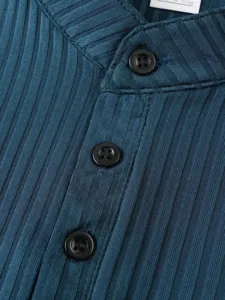 Close-up detail of men's ribbed knit tank top neckline with buttons and vertical stripe texture.