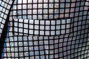 Gros plan détaillé du tissu de blazer pour homme avec grille holographique argentée et poche.