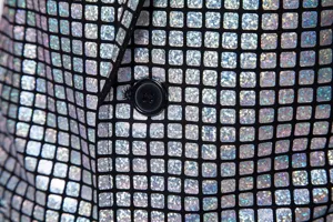 Gros plan détaillé du motif à grille holographique élégant et du bouton sur le blazer homme.