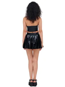 Set top corto e minigonna plissettata in ecopelle nera, outfit lucido da discoteca.