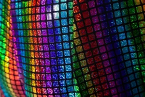 Gros plan détail du tissu à grille de sequins holographiques colorés pour fête homme.