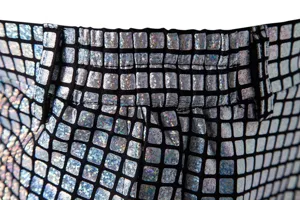 Gros plan détaillé de la ceinture et de la texture de pantalon à grille métallique argentée.