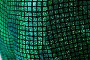 Gros plan détaillé du tissu métallique à sequins verts pour vêtement de scène disco.