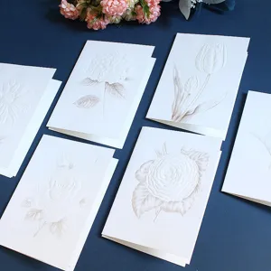 Cartes de vœux botaniques gaufrées blanches avec motifs floraux élégants pour mariages et vœux.