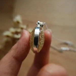 Side view of a vintage glass pendant necklace featuring real dried flowers inside.