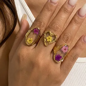 Close-up of vintage gold stainless steel rings with real dried flowers in heart resin