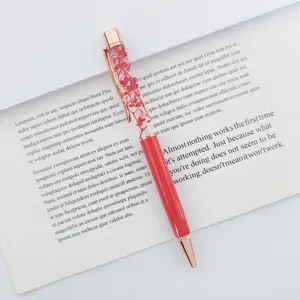 Detailed close-up of a metal ballpoint pen with red dried flowers floating in oil.