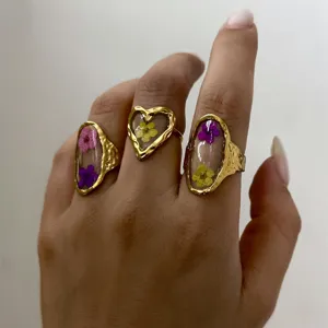 Detailed view of three vintage gold hammered rings with colorful dried flowers in resin