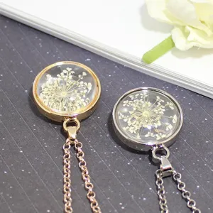 Macro detail of clear glass necklaces with real dried flowers in gold and silver