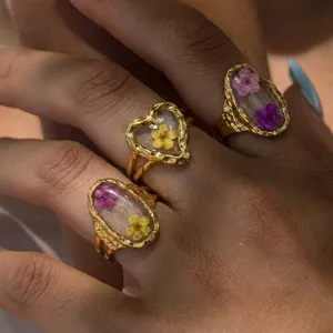 Detail shot of vintage gold-plated rings featuring heart and oval resin-embedded dried flowers